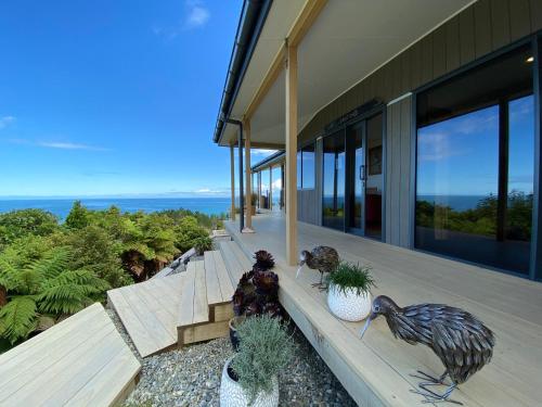 a house with statues of birds sitting on a porch at Tasman Sea Retreat in Punakaiki