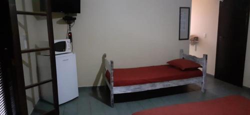 a small room with a bed with a red blanket at VILLA GARDEN - Suites in Maresias