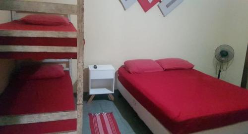 a bedroom with two bunk beds with red sheets at VILLA GARDEN - Suites in Maresias