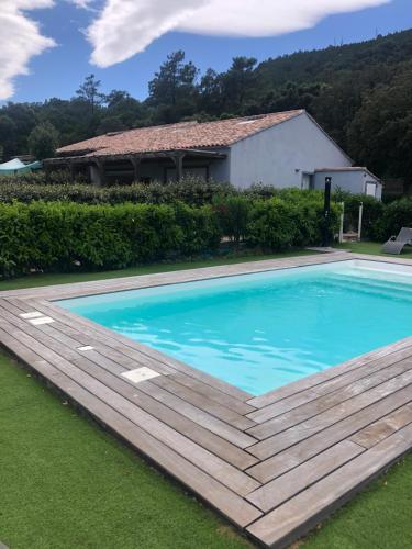 een zwembad met een houten terras voor een huis bij Chez Muriel in Porto-Vecchio