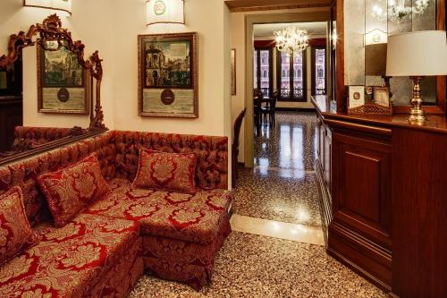 a living room with a red couch and a bar at Antica Locanda Sturion Residenza d'Epoca in Venice