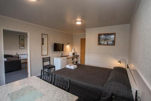 a hotel room with a bed and a living room at Te Anau Top 10 Holiday Park and Motels in Te Anau