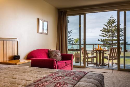 a hotel room with a bed and a view of the ocean at Pebble Beach Motor Inn in Napier