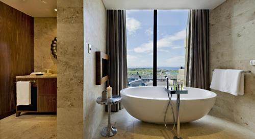 a bathroom with a tub and a large window at Oubaai Hotel Golf & Spa in George