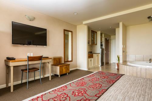 a room with a bathroom with a bed and a tub at Pebble Beach Motor Inn in Napier