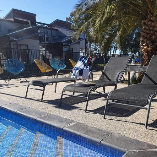 a row of lawn chairs next to a swimming pool at Bundalong Villas in Bundalong