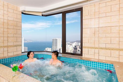 2 personas en una bañera de hidromasaje con vistas a la ciudad en Regalia Gold Hotel, en Nha Trang