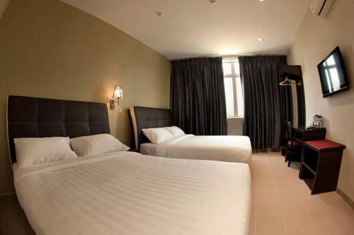 a hotel room with two beds and a television at Ayer Hitam Hotel in Simpang Renggam
