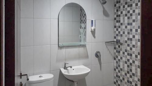 a bathroom with a sink and a toilet and a mirror at RedDoorz Hostel @ Manado Green Hostel in Manado