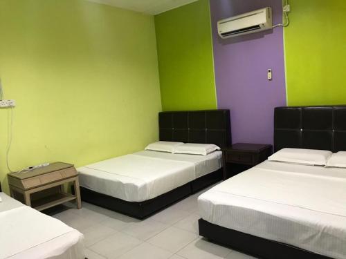 two beds in a room with green and purple at Taman negara rainbow guest house in Kuala Tahan
