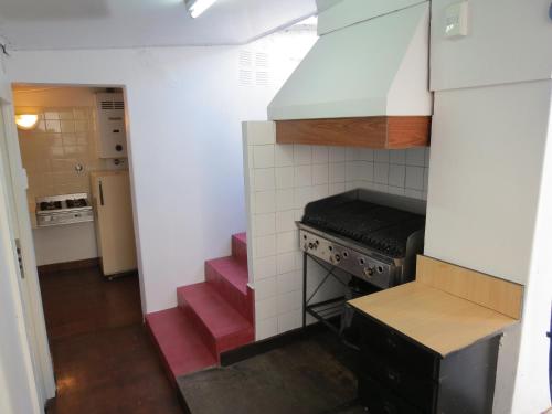 a small kitchen with a stove and pink stairs at Hotel Raglan in Mar del Plata