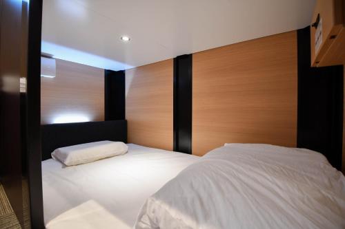 東京にあるH2O STAY Ōtorii - Male Onlyの白いベッド1台(木製ヘッドボード付)が備わるベッドルーム1室が備わります。