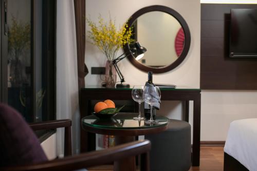 a table with two wine glasses and a mirror at Hanoi Fiesta Hotel & Spa in Hanoi