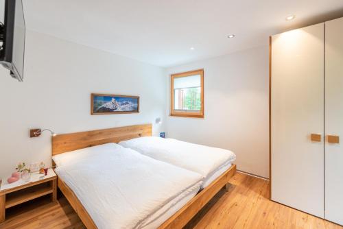 a bedroom with a large white bed and a window at Jolimont Apartments in Zermatt