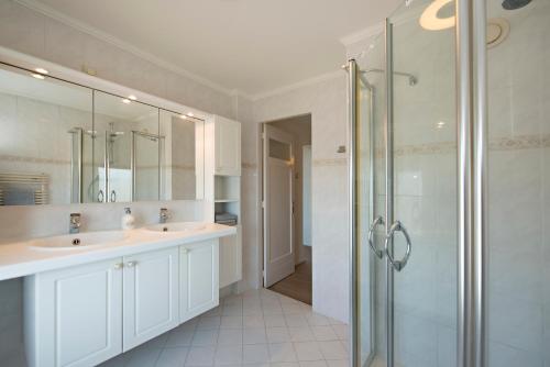 a bathroom with two sinks and a glass shower at Sol Aureus in Middelburg