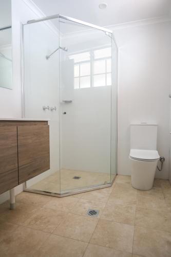 a glass shower in a bathroom with a toilet at Bayview Hotel Woy Woy in Woy Woy