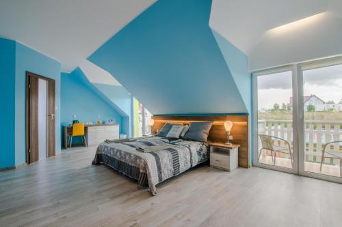 a blue bedroom with a bed and a balcony at Villa Bryza in Mechelinki
