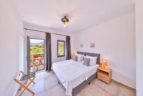 a white bedroom with a bed and a balcony at Thomas Suites Datça in Datca