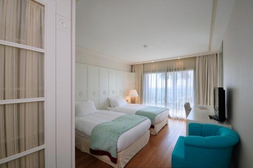 a hotel room with two beds and a blue chair at Hillstone Bodrum Hotel & Spa in Bodrum City