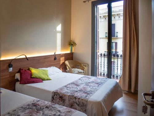 a hotel room with two beds and a window at Pension Ciudadela in Barcelona