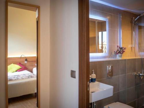 a bathroom with a sink and a mirror and a bed at Pension Ciudadela in Barcelona