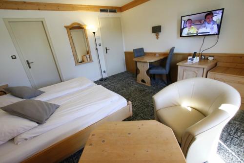 a room with two beds and a chair and a table at Les Portes de la Vallee in Turckheim
