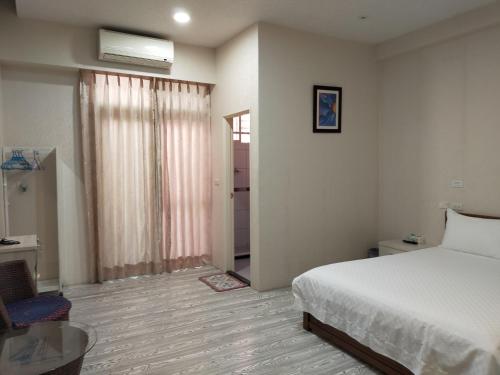 a bedroom with a white bed and a window at Grapefruit Heping Guesthouse in Hualien City