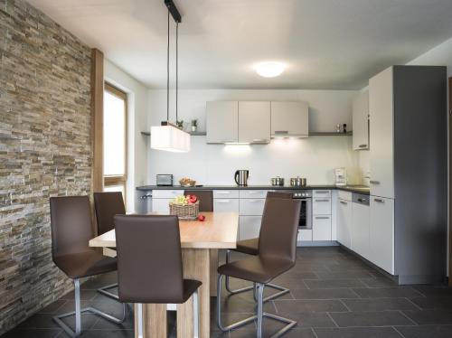 ツェル・アム・ゼーにあるAlpenParks Residence Zell am Seeの白いキャビネット、木製テーブルと椅子付きのキッチンが備わります。