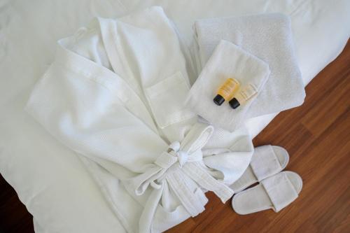 a pile of white towels and a ring on a bed at Winner Sriracha Serviced Apartment in Si Racha