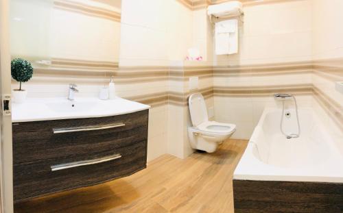 a bathroom with a sink and a toilet and a tub at White Tower Mamaia Apartament in Mamaia