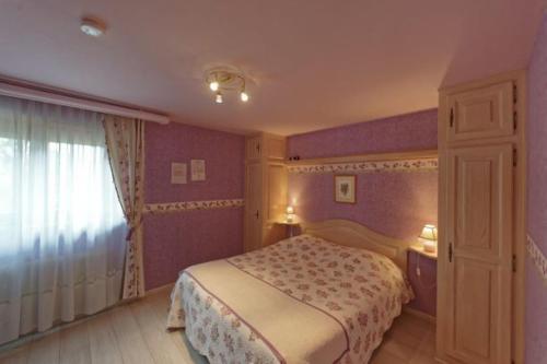 - une chambre avec un lit aux murs violets et une fenêtre dans l'établissement "les amandiers", à Mittelwihr