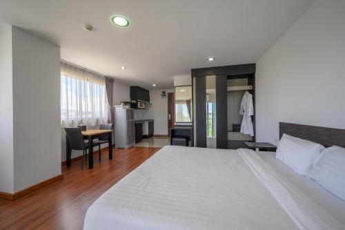 a bedroom with a large white bed and a table at Winner Sriracha Serviced Apartment in Si Racha