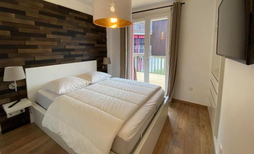 a bedroom with a white bed and a brick wall at Lénoka in La Teste-de-Buch