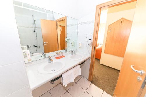 a bathroom with two sinks and a large mirror at Akzent Parkhotel Trebbin in Trebbin