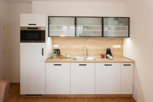 a kitchen with white cabinets and a sink at Apartments Villa Whitehouse in Ostrava