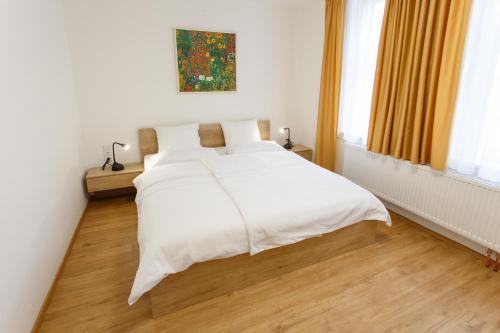 a bedroom with a white bed with white sheets at Apartments Villa Whitehouse in Ostrava