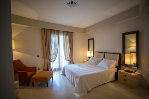 una camera con letto, sedia e specchio di Marinagri Greenblu Hotel & SPA a Policoro