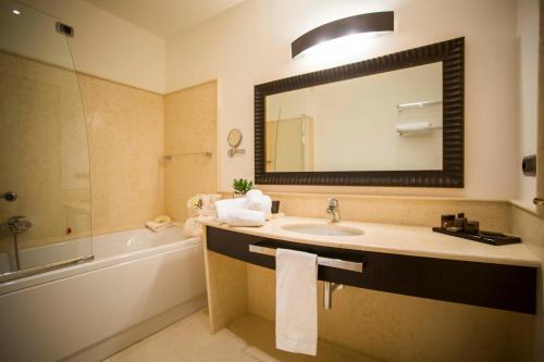 a bathroom with a sink and a mirror and a tub at Marinagri Greenblu Hotel in Policoro