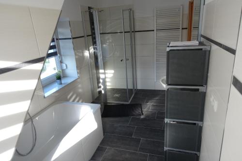 a bathroom with a shower and a white tub at Gästewohnung 16 in Oschersleben