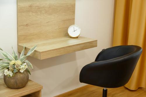 a black chair and a clock on a shelf at Apartments Villa Whitehouse in Ostrava