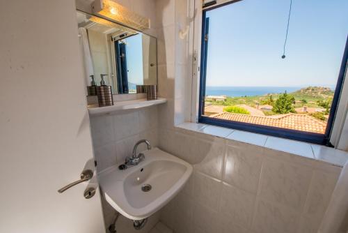 a bathroom with a sink and a window at Ifigenia's Apartments in Stoupa