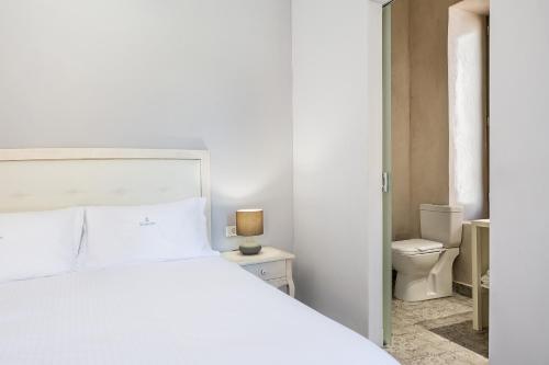 ein Schlafzimmer mit einem weißen Bett und einem WC in der Unterkunft Shalom Luxury Rooms Daliani in Chania