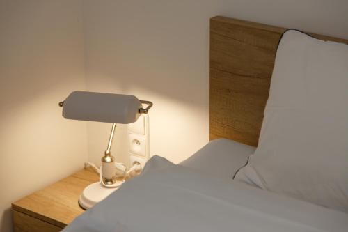 a bedroom with a bed and a lamp on a nightstand at Apartments Villa Whitehouse in Ostrava
