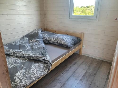 a bed in a room with two pillows on it at Domki Nadmorska fala Rusinowo in Rusinowo