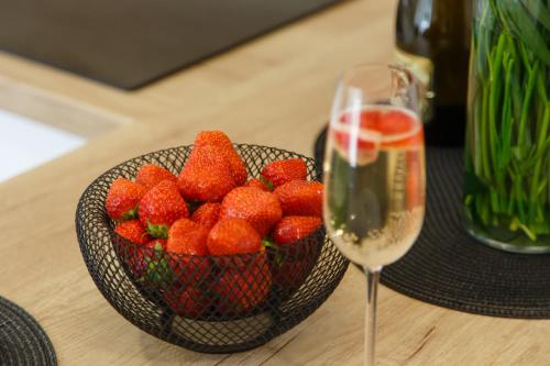 a bowl of strawberries next to a glass of wine at Apartments Villa Whitehouse in Ostrava