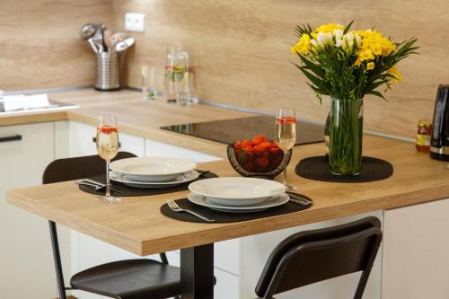 a table with two glasses of wine and a vase of flowers at Apartments Villa Whitehouse in Ostrava