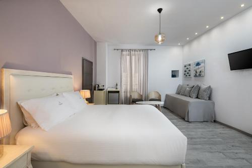 a white bedroom with a large bed and a couch at Shalom Luxury Rooms Daliani in Chania Town