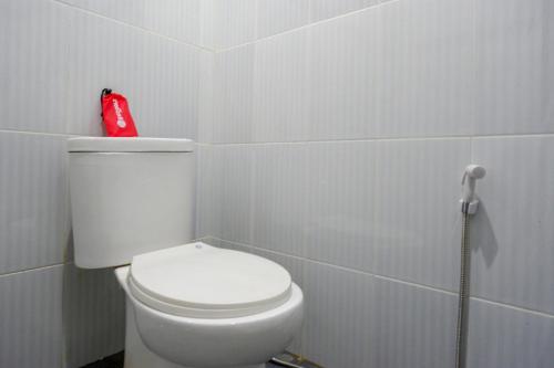 a bathroom with a white toilet and a red container at RedDoorz At Rantepao Toraja Utara in Rantepao