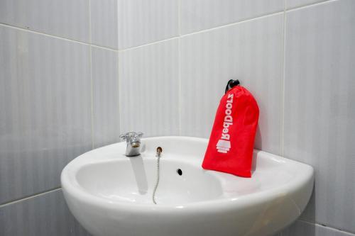 um saco vermelho está sentado num lavatório branco em RedDoorz At Rantepao Toraja Utara em Rantepao