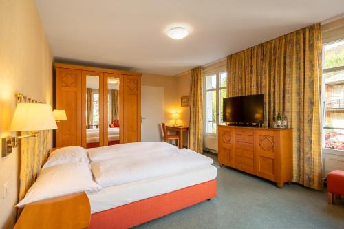 a bedroom with a large bed and a television at Schönbühl Hotel & Restaurant Lake Thun in Thun